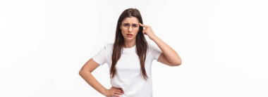 Are you dumb. Portrait of skeptical and bothered, annoyed young woman roll finger over temple and staring with disdain or scorn at person acting crazy, scolding for not thinking before acting.