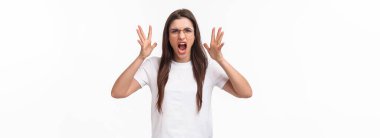 Waist-up portrait of angry, pissed-off brunette pretty girl in glasses, shouting, blaming partner for cheating on her, shaking hands and screaming, having confrontation, frowning aggressive.