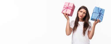 Kutlama, tatiller ve hediye konsepti. İçindekiler çok ilginç. Meraklı genç doğum günü kızının portresi hediye kutularını sallıyor. Arkadaşının ona ne aldığını anlamaya çalışıyor. Beyaz arka plan..