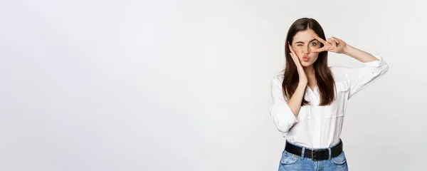 stock image Beautiful girl with healthy skin, showing peace sign on face and winking, standing over white background. People and emotions concept.