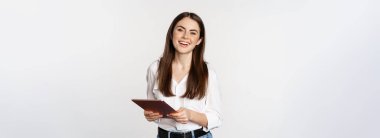 Gülümseyen modern kadın dijital tabletle duruyor, gülüyor ve mutlu görünüyor, çalışıyor, beyaz stüdyo arka planına karşı poz veriyor..