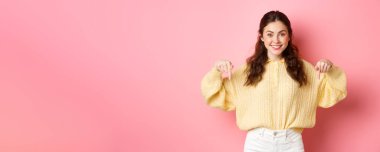 Fotokopi alanını gösteren, tanıtım metnini veya logosunu gösteren, pembe arka planda duran genç çekici kadın modelinin portresi.