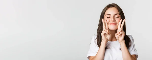 stock image Close-up of happy smiling brunette girl close eyes and showing peace gestures, having fun.