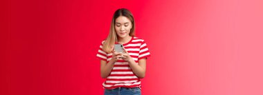 Popüler Asyalı kadın yaşam tarzı blogcu internete fotoğraf yüklüyor akıllı telefon görüntüsü parşömen görüntüsü, gülümseyen kadın cihaz standı kırmızı arka plan kullanarak rahatlamış. Boşluğu kopyala