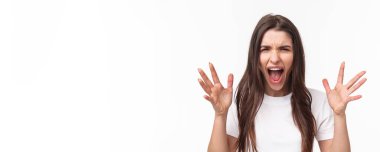 Close-up portrait of angry, pissed-off aggressive woman screaming at person, shouting and shaking hands from anger and disappointment, grimacing bothered, standing furious white background.