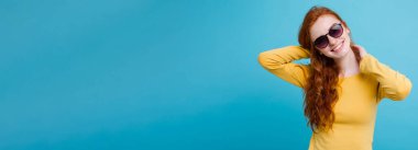 Kameraya bakarak gülen çiller ile mutlu Kızıl kızıl saçlı kız portresi. Pastel mavi arka plan. Kopya alanı.