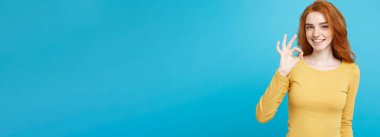 Eğlenceli ve insanlar kavramı - Headshot portre çekici Kızıl kızıl saçlı kız gülümseyerek ve ok işareti ile parmak yapma çilli. Pastel mavi arka plan. Kopya alanı