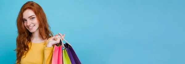 ショッピングのコンセプト ショッピング バッグとカメラを見て笑っている肖像若い美しい魅力的な Redhair 女の子をクローズ アップ 青いパステル背景 コピー スペース — ストック写真