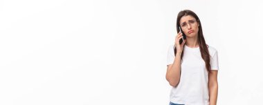 İletişim, teknoloji ve yaşam tarzı kavramı. Kasvetli ve üzgün genç bir kadının portresi. Birini arıyor ve telefonu kapatıyor. Cevap bekliyor, somurtuyor ve kaşlarını çatıyor..