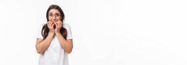 Panik içinde korkmuş esmer bir kızın belden yukarı portresi. Sınavlar neredeyse korkmuş, ısıran parmaklar ve dehşete düşmüş, titreyen korku dolu, beyaz arka planda korkuyla dikilen bir bakış..