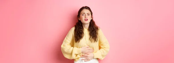 年轻女人肚子痛 双手放在肚子上 感到可怕的疼痛 月经抽筋 站在粉红的背景下 复制空间 — 图库照片
