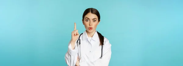 Młody Lekarz Kobieta Lekarz Białym Płaszczu Podnoszący Palec Wskazując Sugerując — Zdjęcie stockowe