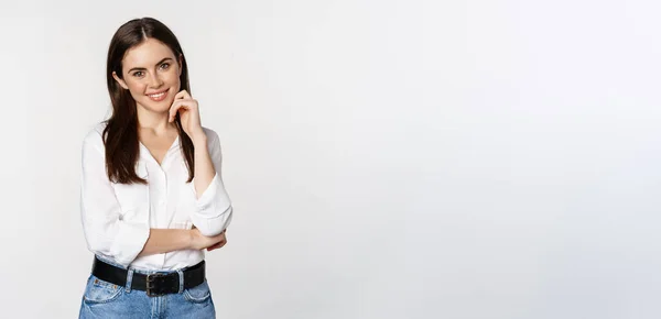 stock image Smiling young businesswoman, female entrepreneur in white shirt, cross arms on chest like professional, standing over studio background.