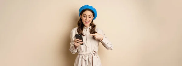 Portrait Stylish Modern Woman Outerwear Pointing Mobile Phone Screen Looking — Zdjęcie stockowe