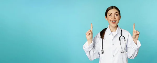 Ενθουσιαστικός Ιατρός Νεαρή Γυναίκα Γιατρός Λευκό Παλτό Στηθοσκόπιο Δείχνει Διαφήμιση — Φωτογραφία Αρχείου
