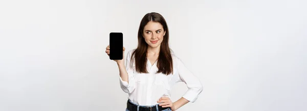 Lächelnde Frau Mit Handybildschirm Listig Dreinblickend Vor Weißem Hintergrund Stehend — Stockfoto