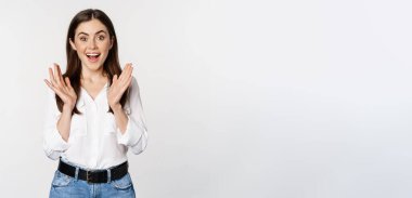 Enthusiastic laughing woman, smiling amused, clapping hands, applausing, standing in formal outfit over white background.
