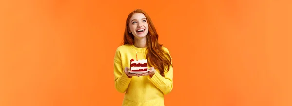 誕生日を祝う夢のような幸せな女の子 楽しみを持っています 笑いと左上隅思慮深く見て おいしい上にろうそくを吹き出すように願いを作ります おいしい作品B日ケーキ オレンジの背景 — ストック写真