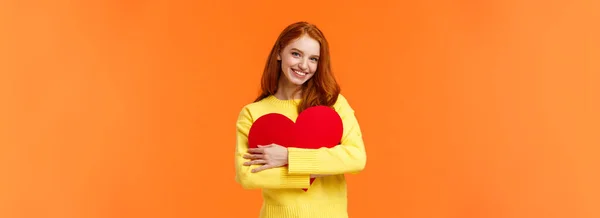 バレンタインデー ロマンスまたは関係の概念 彼女の愛する人を待っている公開され 美しい赤毛の女の子は バレンタインカードを受け取り 大きなハートサインを抱き 幸せな笑顔 立ってオレンジの背景 — ストック写真