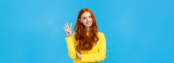 stock image Consumer, shopping and fashion concept. Attractive ginger girl, redhead woman making reservetion, place order four products, smiling and gazing friendly camera, counting with fingers, blue background.
