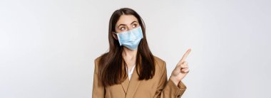 Coronavirus ve insanlar konsepti. İş yerindeki yüz maskesi takan iş kadını portresi logoyu işaret ediyor, şirket afişi, beyaz arka plan..