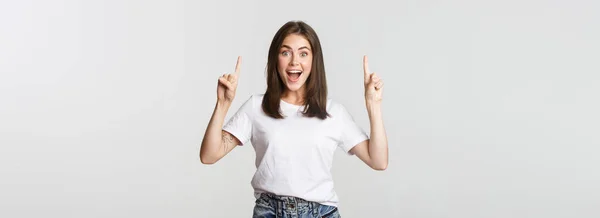 Atrakcyjny Uśmiech Brunetka Dziewczyna Wskazując Palce Górę Pokazując Logo — Zdjęcie stockowe