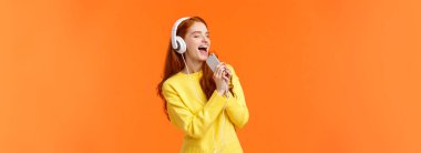 En sevdiğin parçayı dinlerken kendini kaptıran bir kız. Güzel kızıl saçlı kadın, doğum günü için ailelerin aldığı yeni kulaklıklarla müzik dinlemeyi seviyor. Akıllı telefonları kapalı tutuyor ve karaoke yaparcasına mikrofonda şarkı söylüyor..