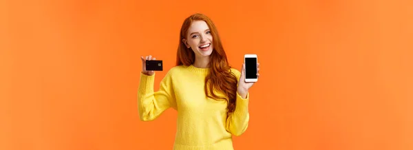 在线和金融概念 兴高采烈的红头发年轻女性开设了银行账户 手持智能手机和信用卡 面带微笑 推荐使用网上购物应用程序 — 图库照片