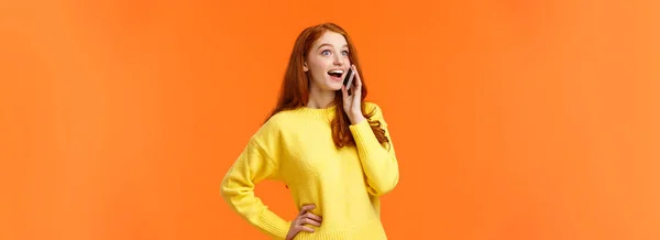 携帯電話で話している間に友人から良いニュースを聞いて 耳の近くにスマートフォンを持っている 会話をしている オレンジの背景 — ストック写真