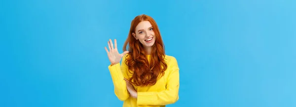 陽気でカリスマ的なフレンドリーな赤毛の女性は パーティーのための注文 予約または予約場所として5位 黄色のセーターで屈託のない青の背景に立っている — ストック写真