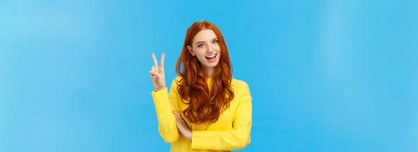 黄色のセーターで陽気発信と幸せなカリスマ赤毛の女性 平和の兆候を示します 数2または2倍と笑顔 購入を行います ダブルチーズを注文 青の背景 — ストック写真