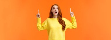 Vay canına. Şaşırmış ve şaşırmış kızıl saçlı kız tatil özel promosyonunu kesiyor, kadın dik dik bakıyor ve işaret ediyor, harika bir teklif sunuyor, turuncu arka planı hayrete düşürüyor..