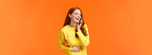 コミュニケーション テクノロジー 人々の概念 陽気なかなり赤毛のヒップスターの女の子の電話で話して 屈託のない笑い 腹を閉じる目 耳の近くのスマートフォン オレンジの背景に触れる — ストック写真