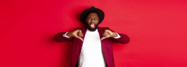 Noel alışverişi ve insanların konsepti. Siyahi adamın dil göstermesi iğrençtir. Kötü bir şeyden hoşlanmaz, kötü bir ürünü yargılar, kırmızı arka plan..