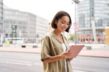 Tabletle yürüyen, şehirde bir yerlere giden zarif bir kadının portresi..
