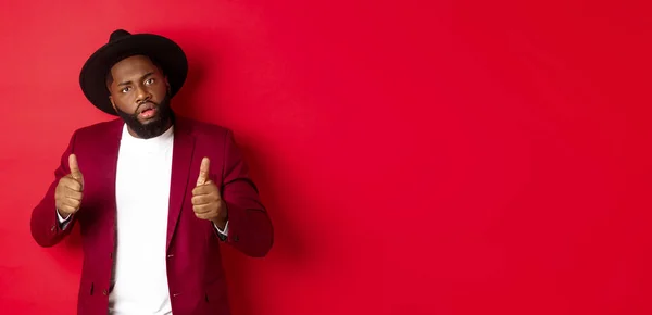 stock image Impressed Black man saying good job, cheer up with thumbs-up, praise something, standing against red background. Copy space