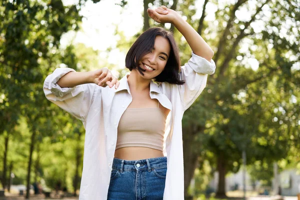 stock image Carefree woman dancing and walking in park with hands lifted up high, smiling happily. Lifestyle concept.