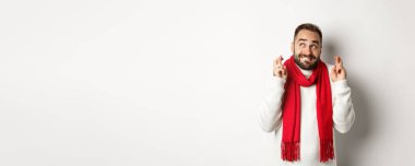 Noel tatili ve yeni yıl konsepti. Umut dolu bir adam dua ediyor, hediyeler bekliyor, beyaz arka planda duruyor..