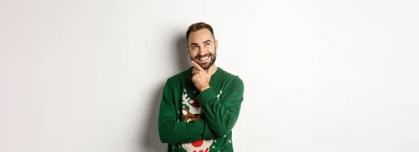 新年のお祝いと冬の休日のコンセプト 左上の隅を見て笑顔白い背景を見てクリスマスの贈り物について考える素敵な男 — ストック写真