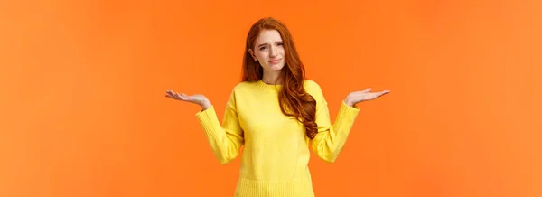 バカバカしい質問を聞いてる黄色のセーターの不注意で面倒なかわいい赤毛の女性は 手を横に上げ 優柔不断な顔をしかめ 混乱感と肩をすくめる — ストック写真