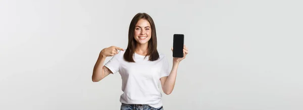 Senyum Menarik Wanita Menunjuk Jari Layar Smartphone Latar Belakang Putih — Stok Foto