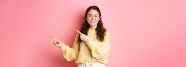 Bu tarafa bak. Gülümseyen güzel bir kadın model, parmaklarını telif boşluğunu işaret ediyor, reklamları gösteriyor, kameranın iyimser ritmine bakıyor, pembe arka planda duruyor..