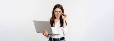 Shocked woman looking at laptop screen confused, stunned about smth on computer, standing over white background.