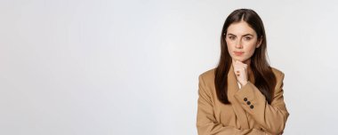 İş kadını düşüncesi, şirket kadını düşünceli görünüyor, karar veriyor, kahverengi takım elbiseyle beyaz arka planda duruyor..