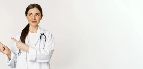 Mosolygó Fiatal Doktornő Egészségügyi Dolgozó Portréja Bal Oldali Ujjal Mutogatás — Stock Fotó