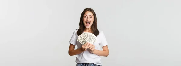 幸せな魅力的なブルネットの女の子保持お金と笑顔興奮し 白い背景 — ストック写真