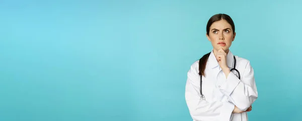 Νεαρή Γυναίκα Γιατρός Νοσηλεύτρια Λευκό Παλτό Σκέφτεται Και Κοιτάζει Αλλού — Φωτογραφία Αρχείου
