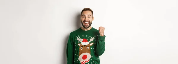 크리스마스 스웨터를 흥분하고 남자가 주먹을 날리고 승리하고 선물과 기쁨을 받으며 — 스톡 사진