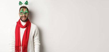 Noel, yeni yıl ve kutlama konsepti. Yakışıklı sakallı adam şaşırmış görünüyor. Parti gözlüğü ve aksesuar takıyor. Beyaz bir geçmişi var..