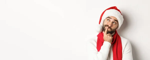 新年のパーティーや冬の休日のコンセプト サンタの髭の男のクローズアップ左上隅で思慮深く見える帽子 思考や意思決定 クリスマスの贈り物を選ぶ 白い背景 — ストック写真